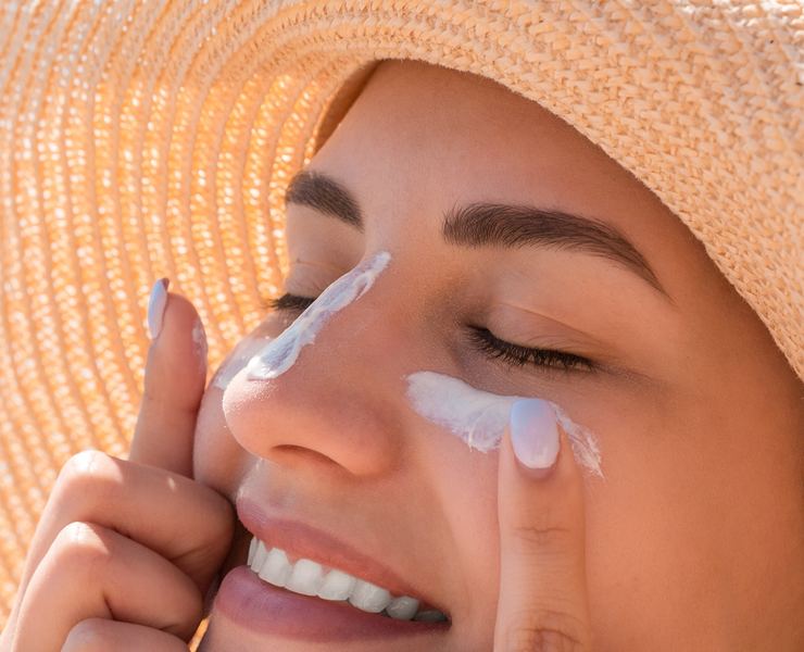Mujer aplicando crema solar en el rostro