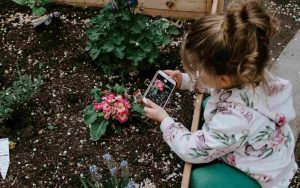 Niña fotografiando una flor - Unsplash